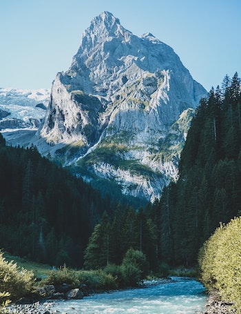 photo of a river, trees, and a mountain peak in the Swiss Alps